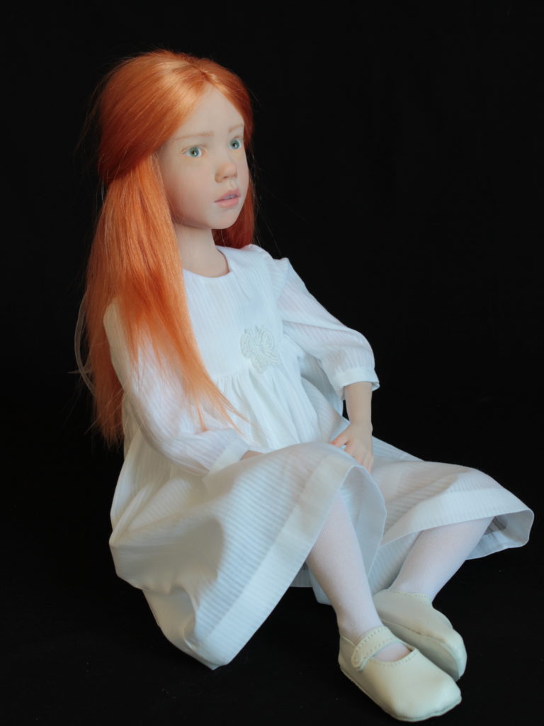 "Petite fille rousse assise en blanc"
