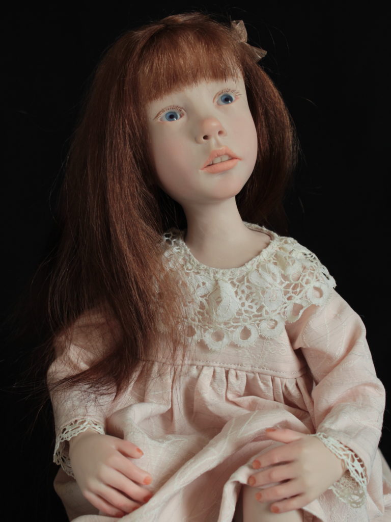 "Petite fille brune assise en robe rose pâle"