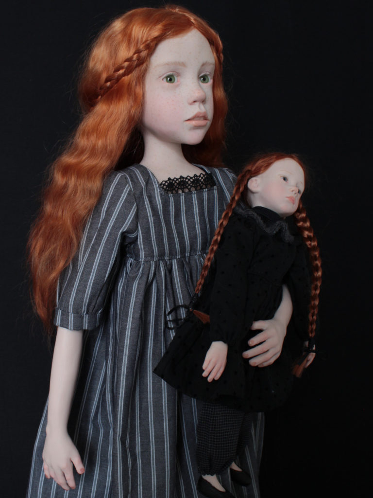 "Petite fille rousse portant une poupée habillée en noir"