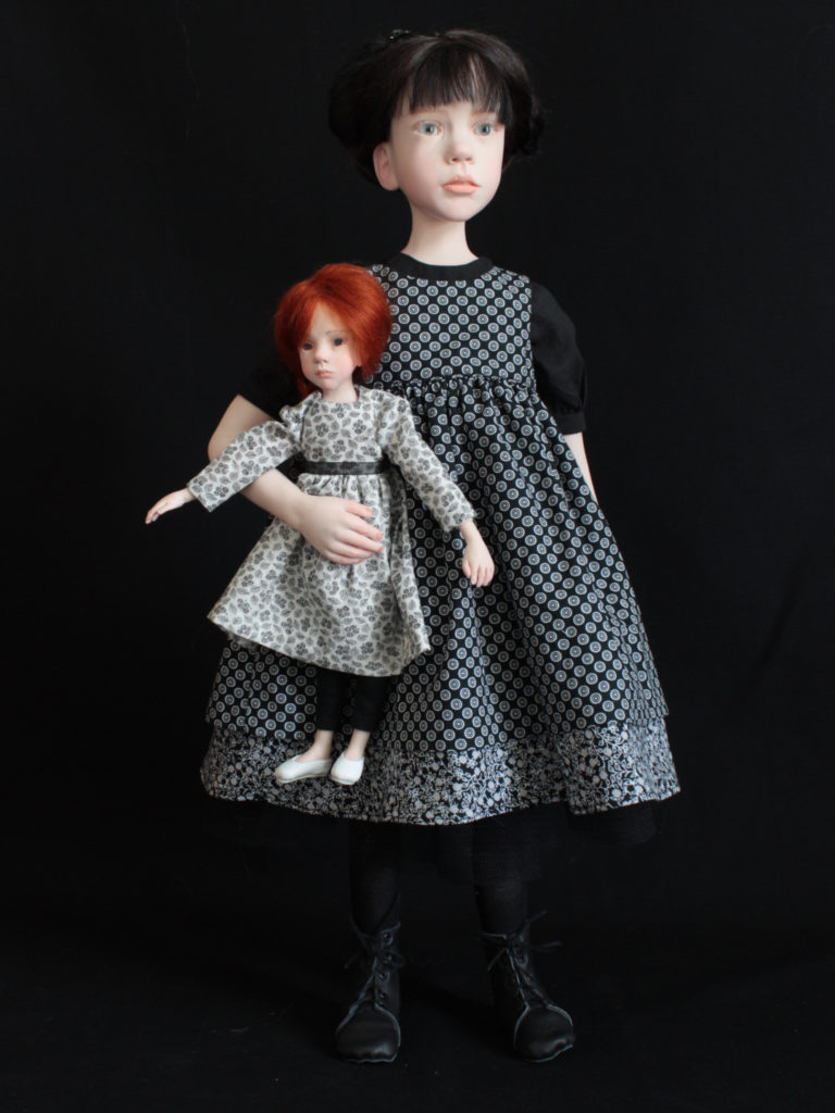 "Petite fille brune en noir avec une poupée"