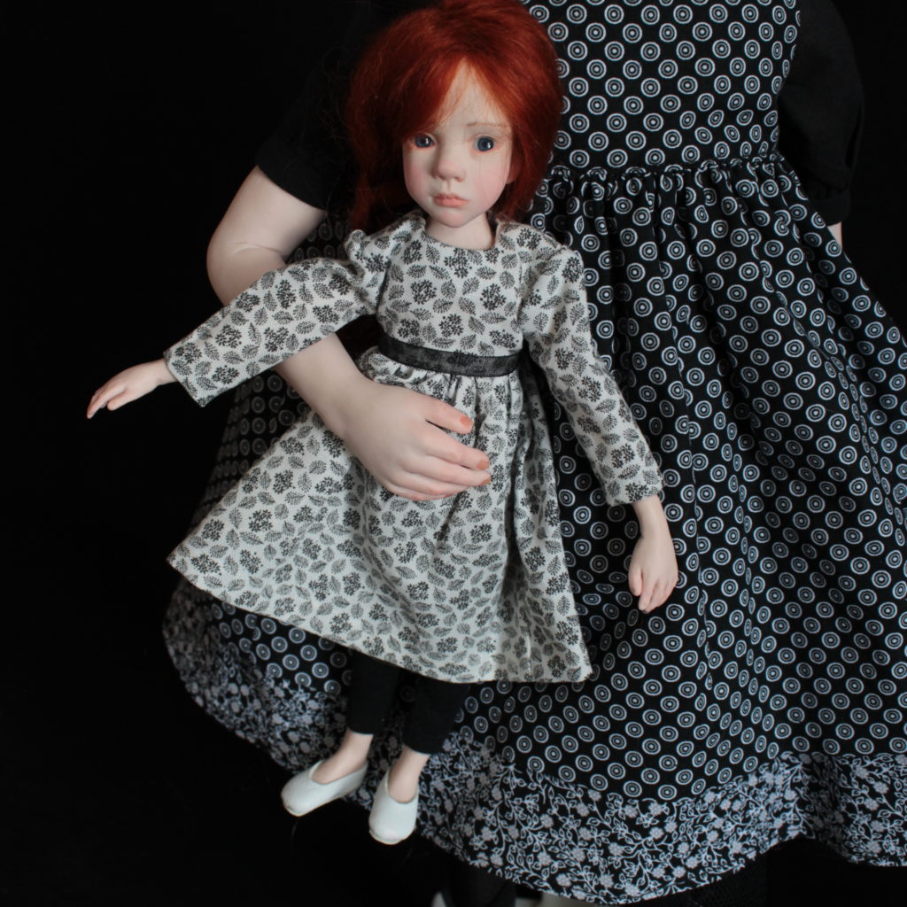 "Petite fille brune avec une robe noire et une poupée"